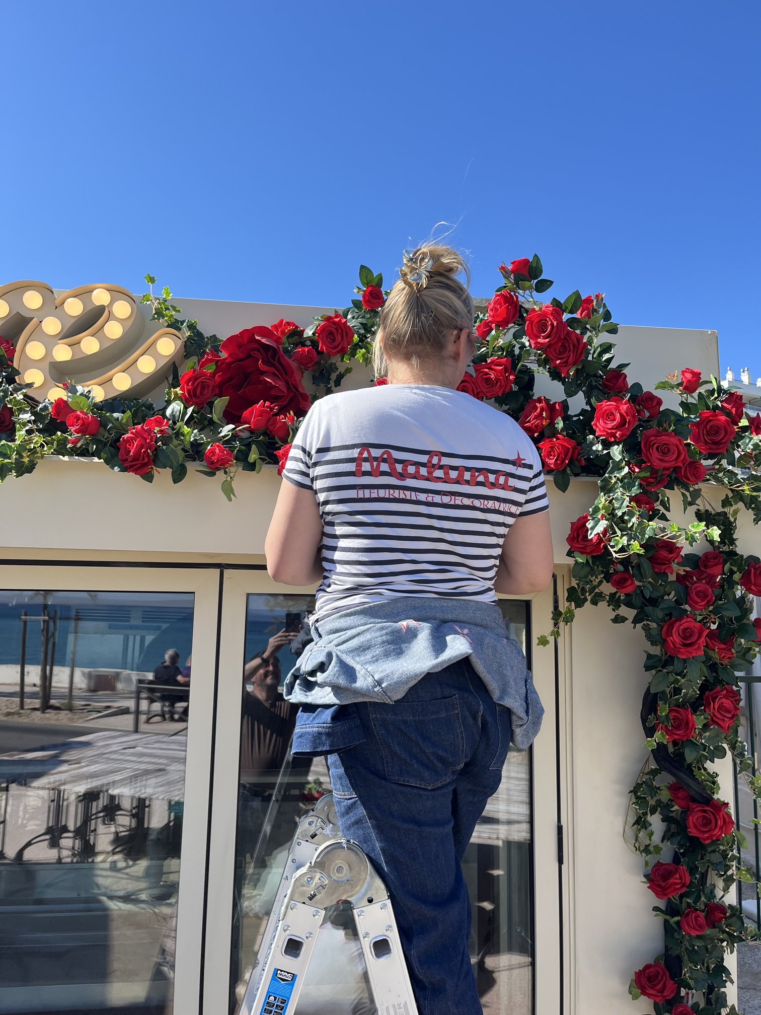 Installation de roses artificielles rouges au-dessus de l'enseigne du restaurant Amore