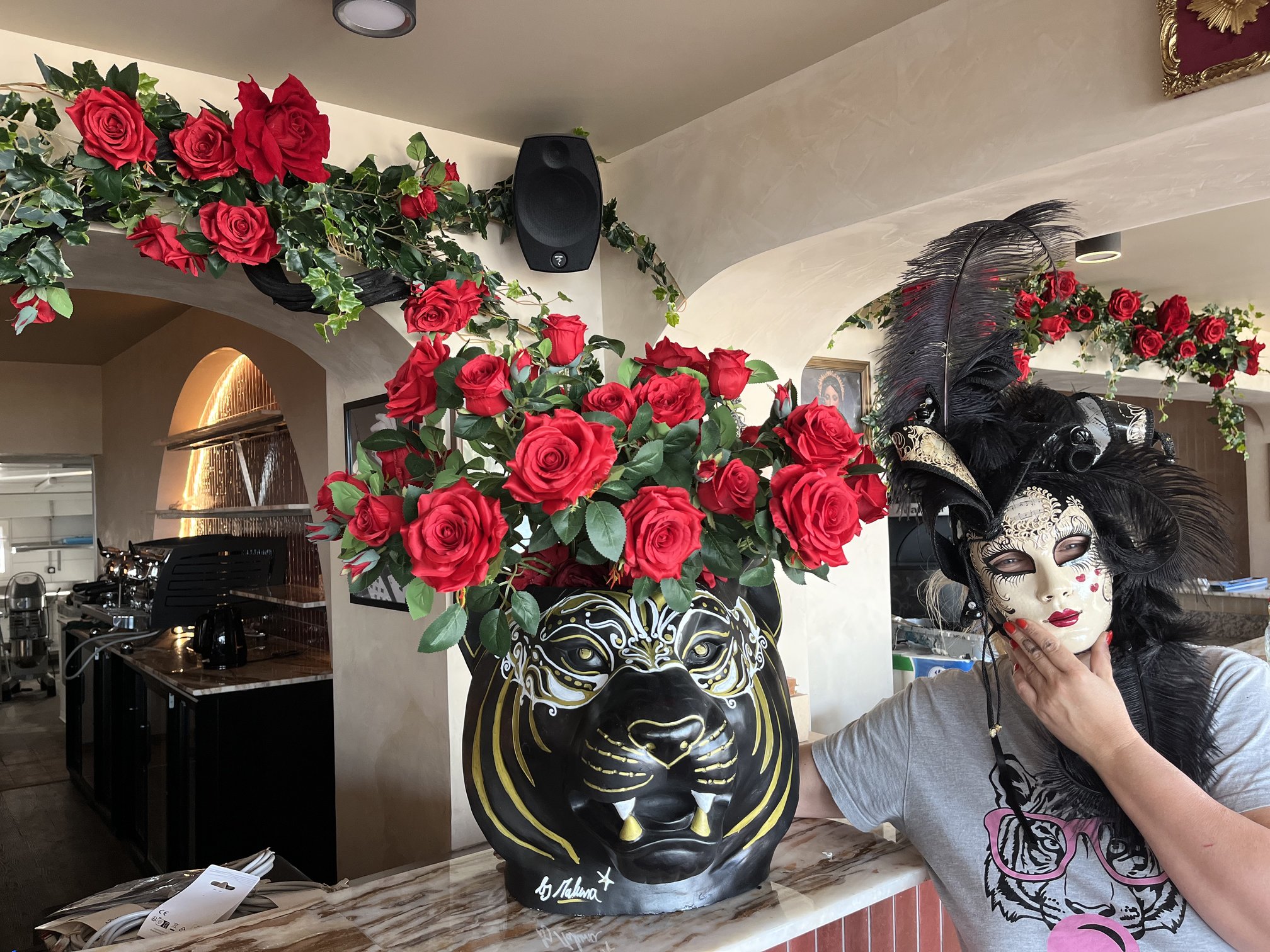 Bouquet de roses rouges artificielles dans un vase en forme de tête de tigre peinte, restaurant Amore