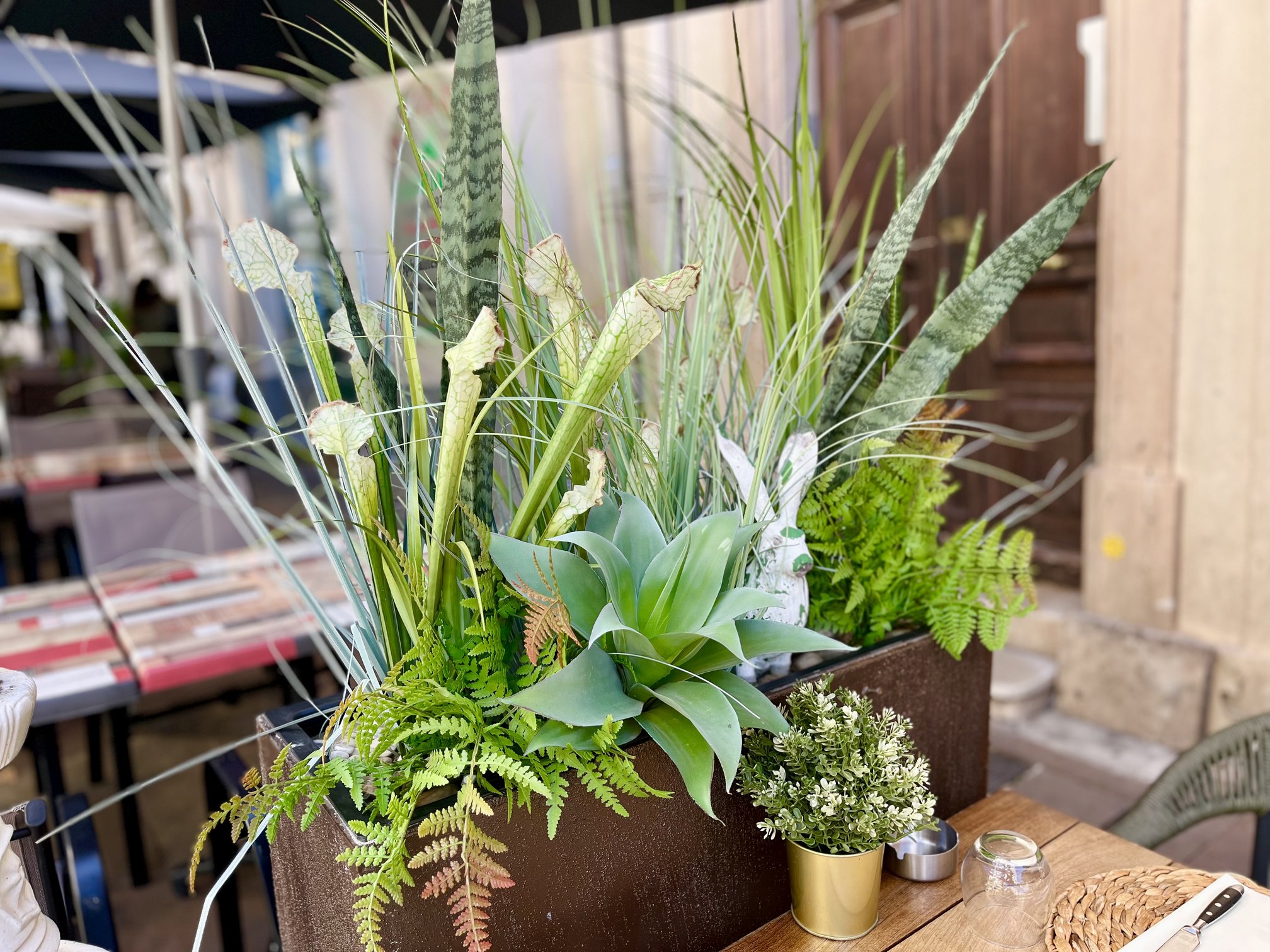 Jardinière extérieure en plantes artificielles variées devant le Ô Bistro des Artistes