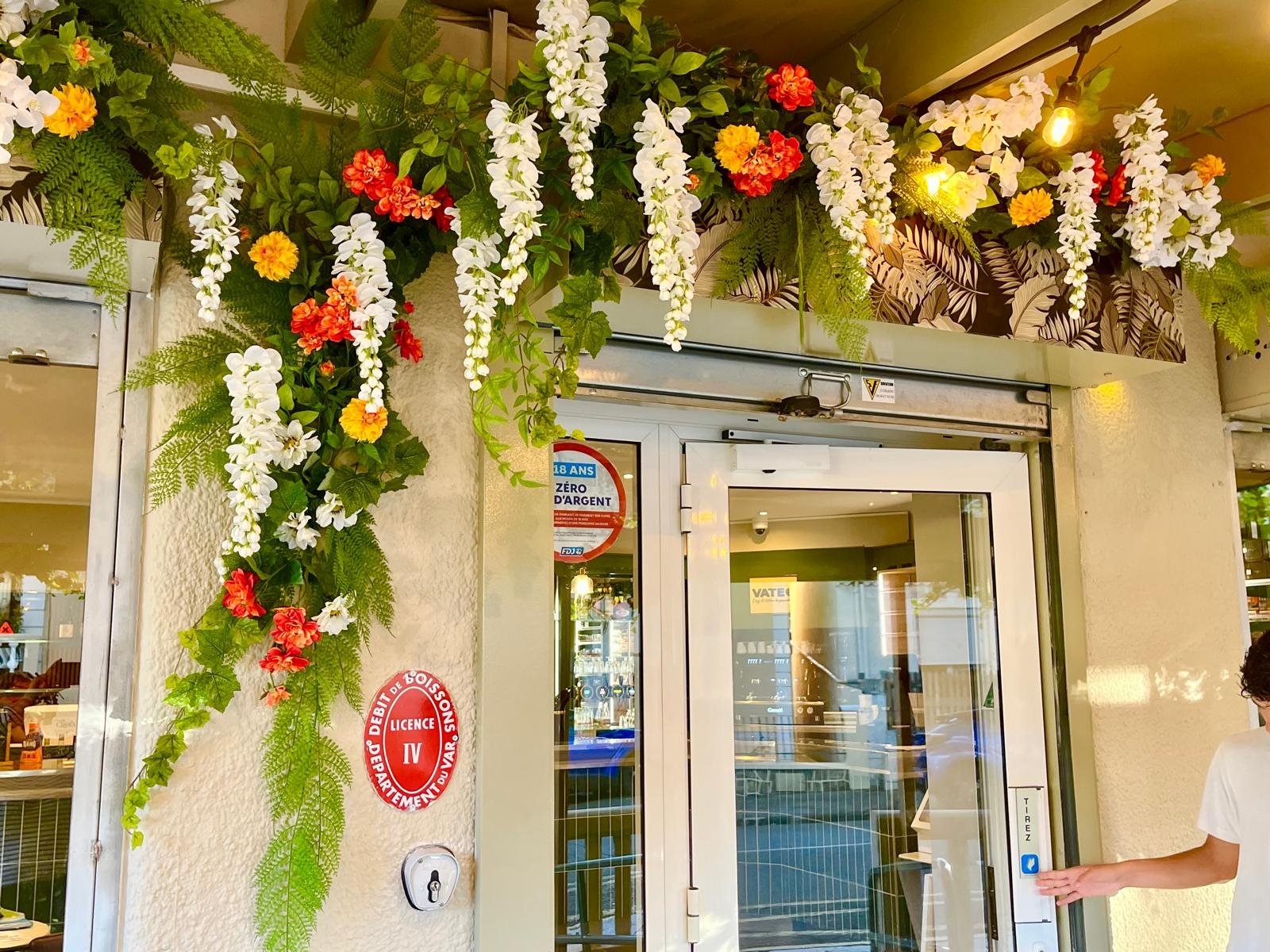 Détail de la guirlande florale artificielle au-dessus de l'entrée du Café des Amis
