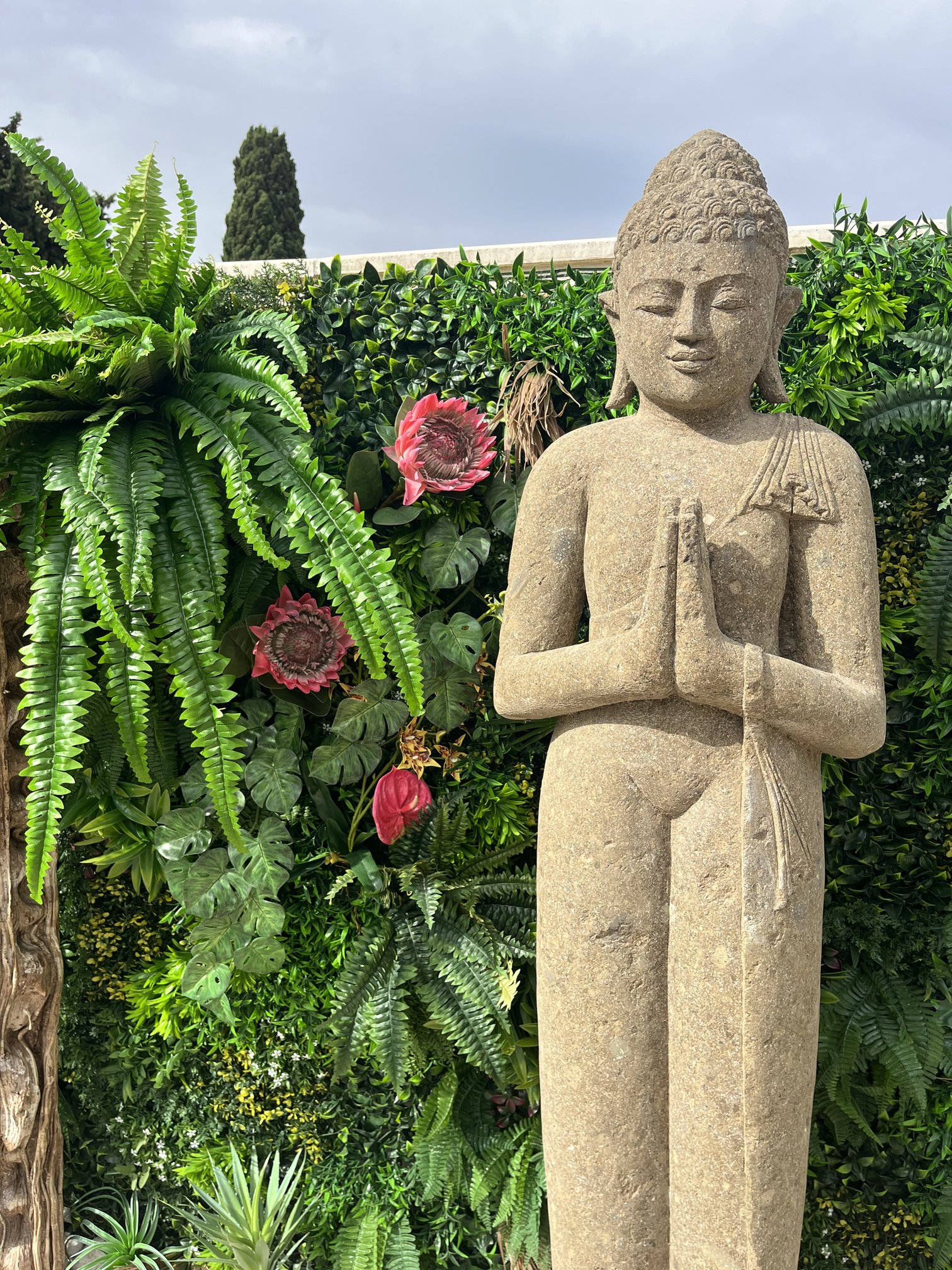 Statue de Bouddha artificielle devant un mur végétal fleuri, jardin privé aménagé par Maluna