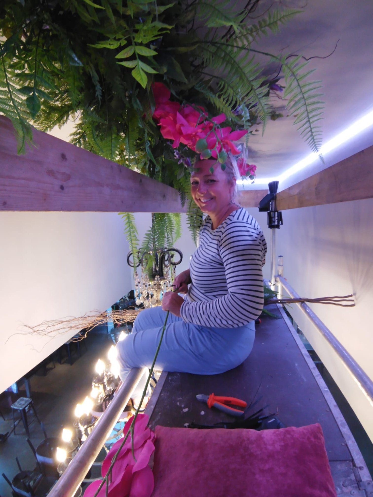 Rosemarie installant une composition florale rose sur l'échafaudage du restaurant La Technopole