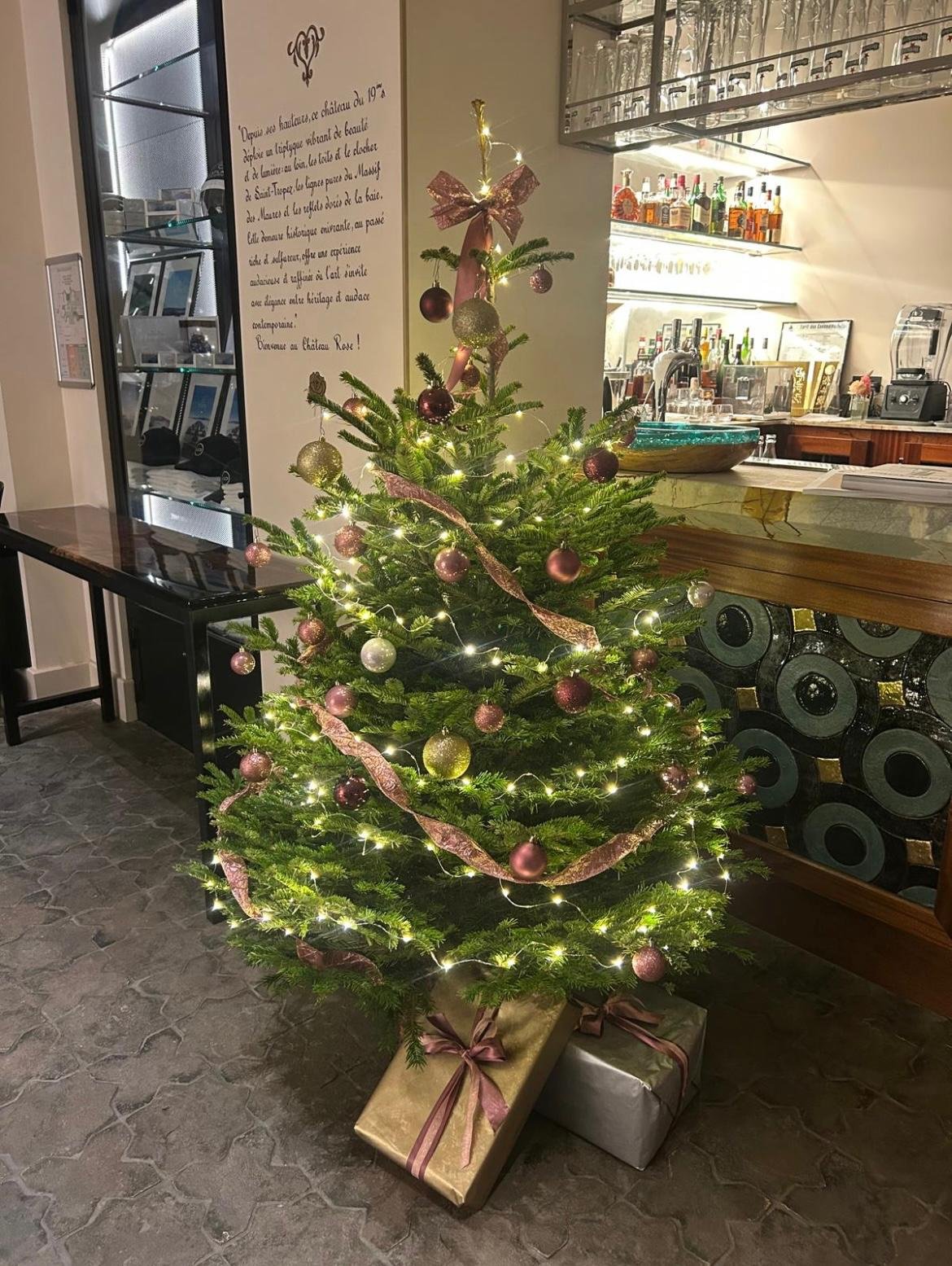Sapin de Noël décoré de boules et rubans roses dorés au bar de l'hôtel Château Rose
