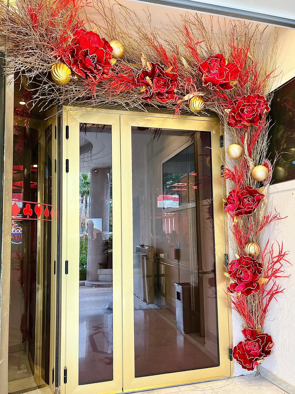 Décoration de Noël en fleurs rouges et branches dorées sur une porte latérale du Casino Partouche Bandol