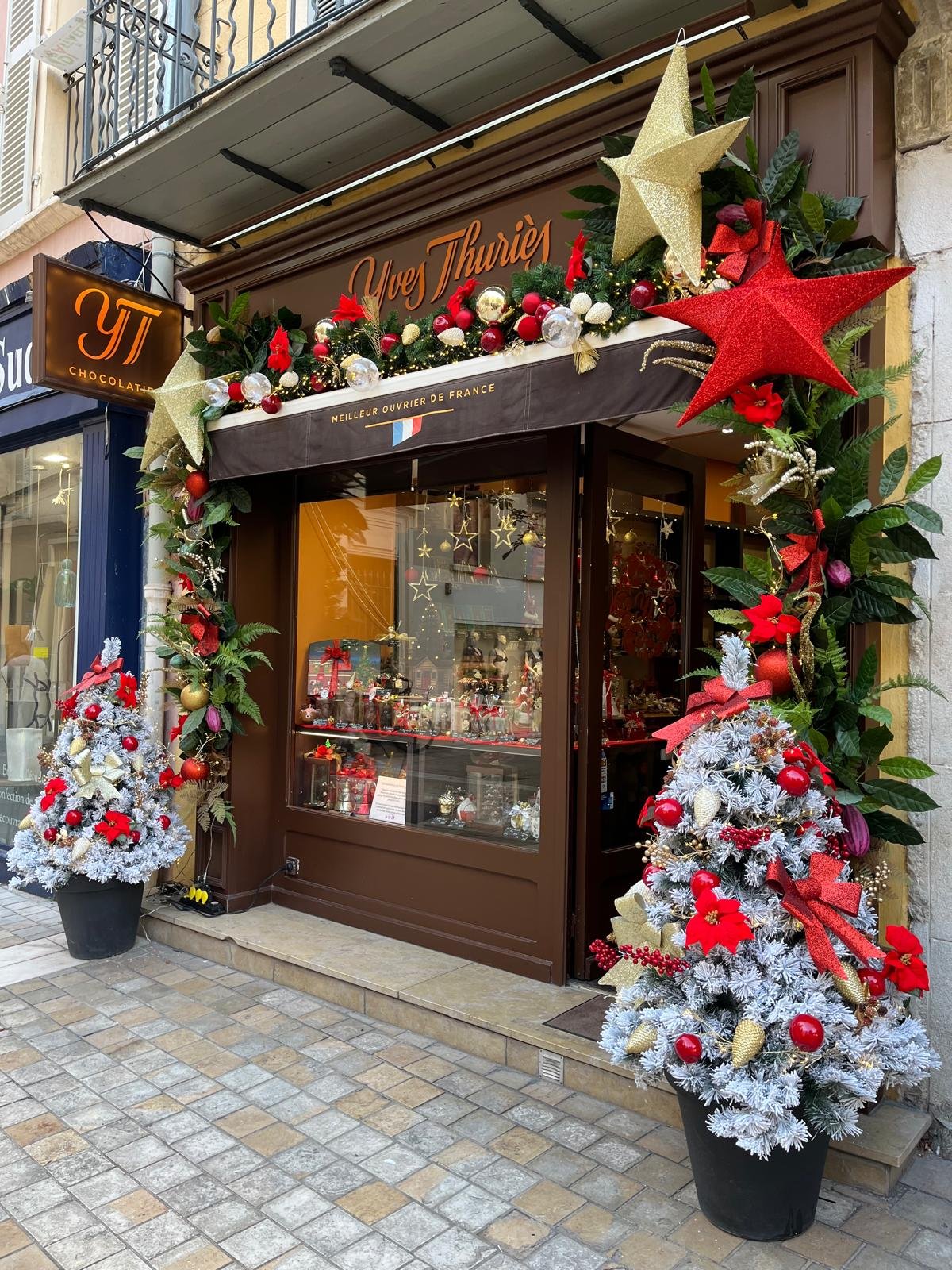 Devanture de la chocolaterie Yves Thuriès décorée d'étoiles et guirlandes de Noël rouges et dorées