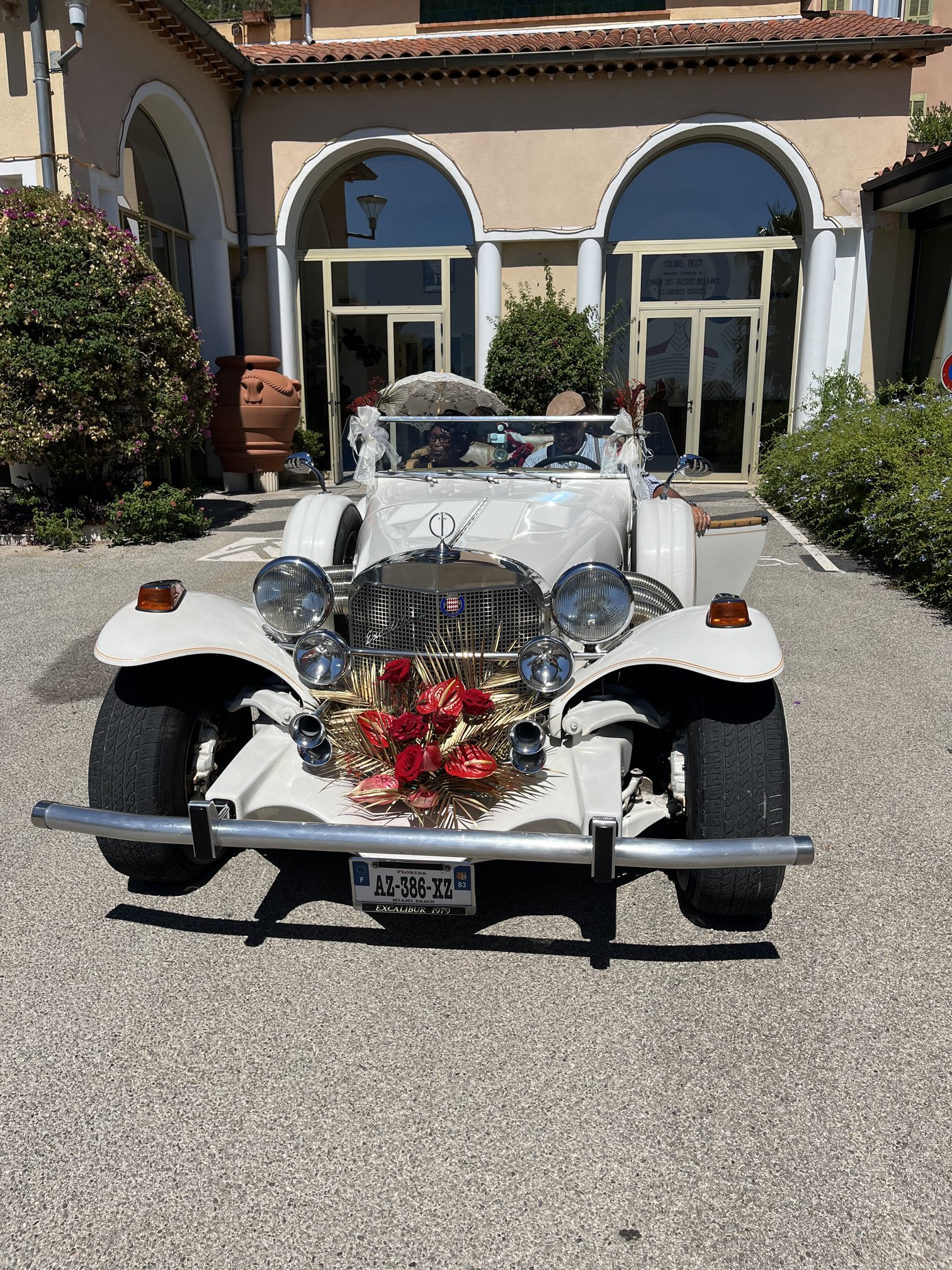 Voiture de collection Excalibur décorée de roses et fleurs artificielles rouges pour le mariage de Prisca et Yannick