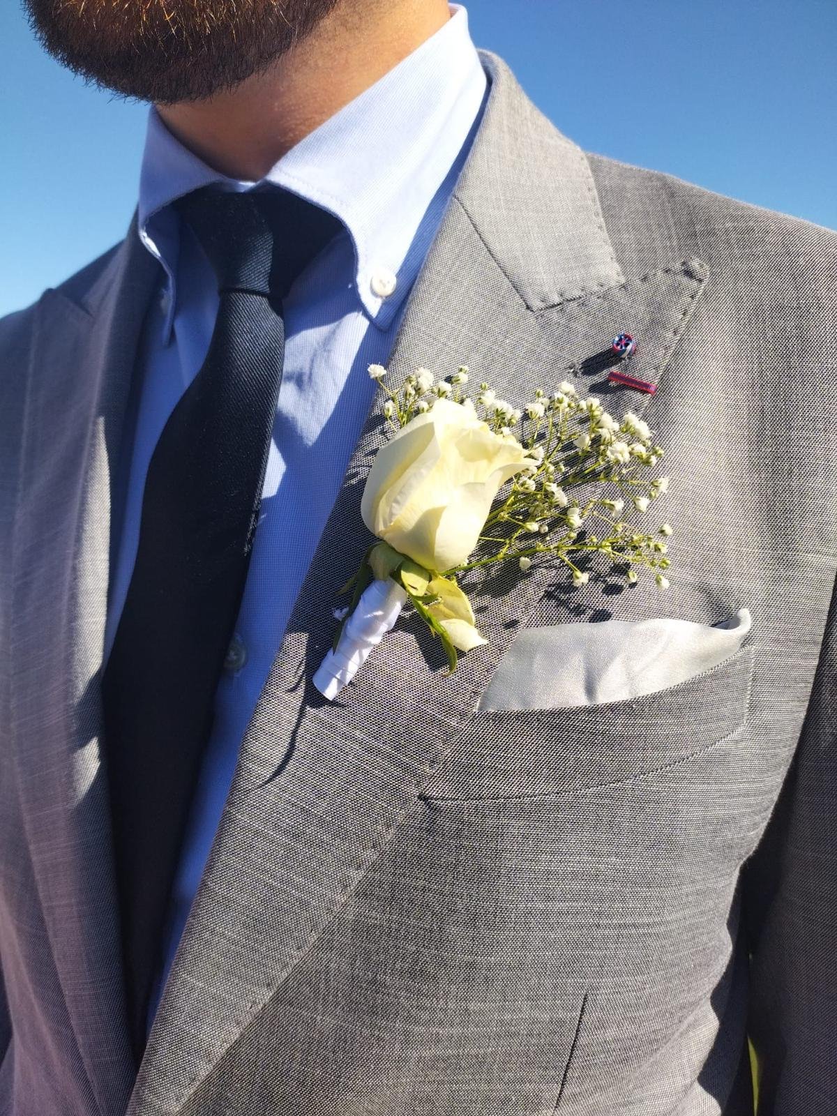 Boutonnière du marié en rose blanche et gypsophile