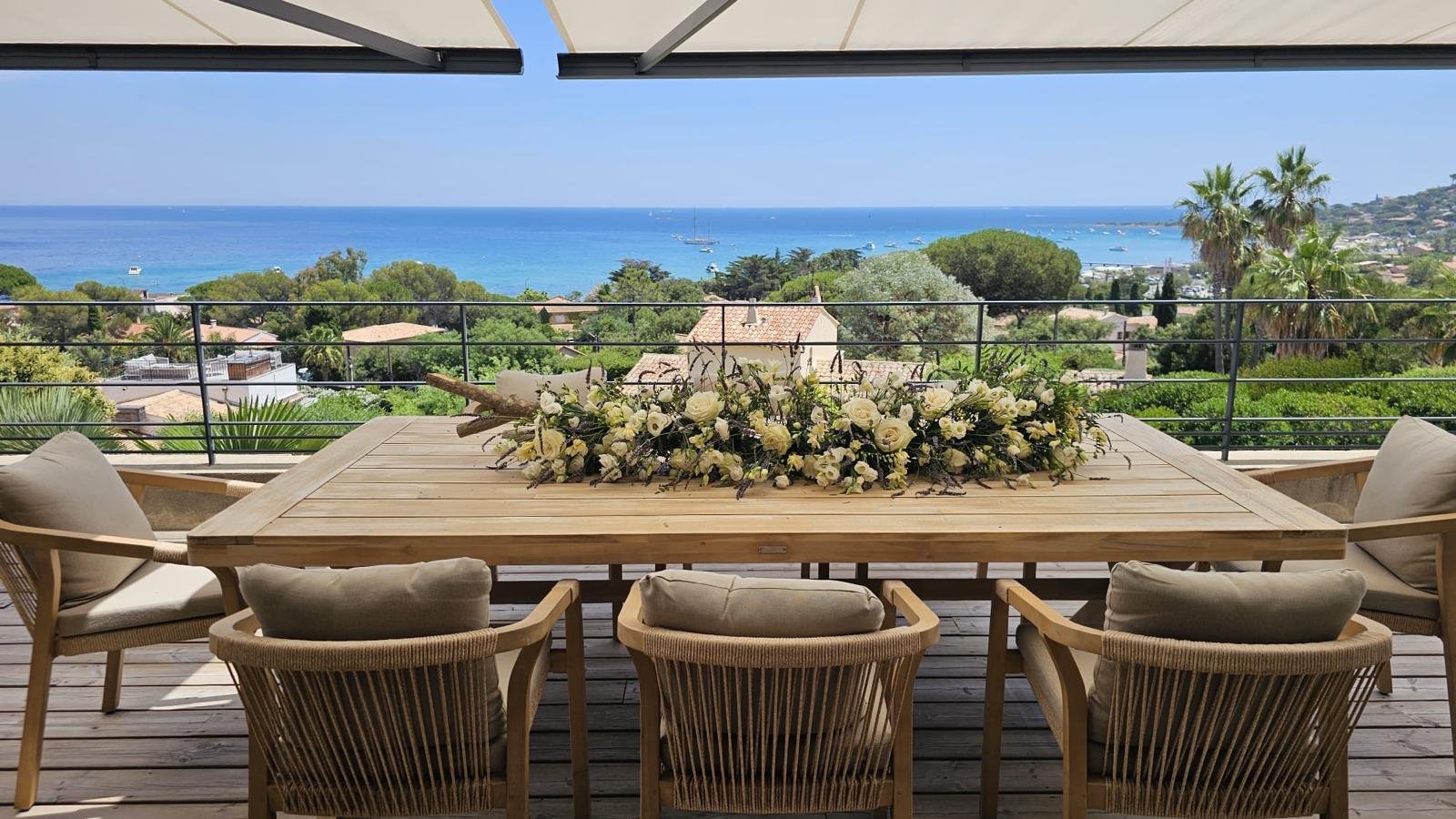 Centre de table en roses blanches et lavande sur une terrasse dominant la mer