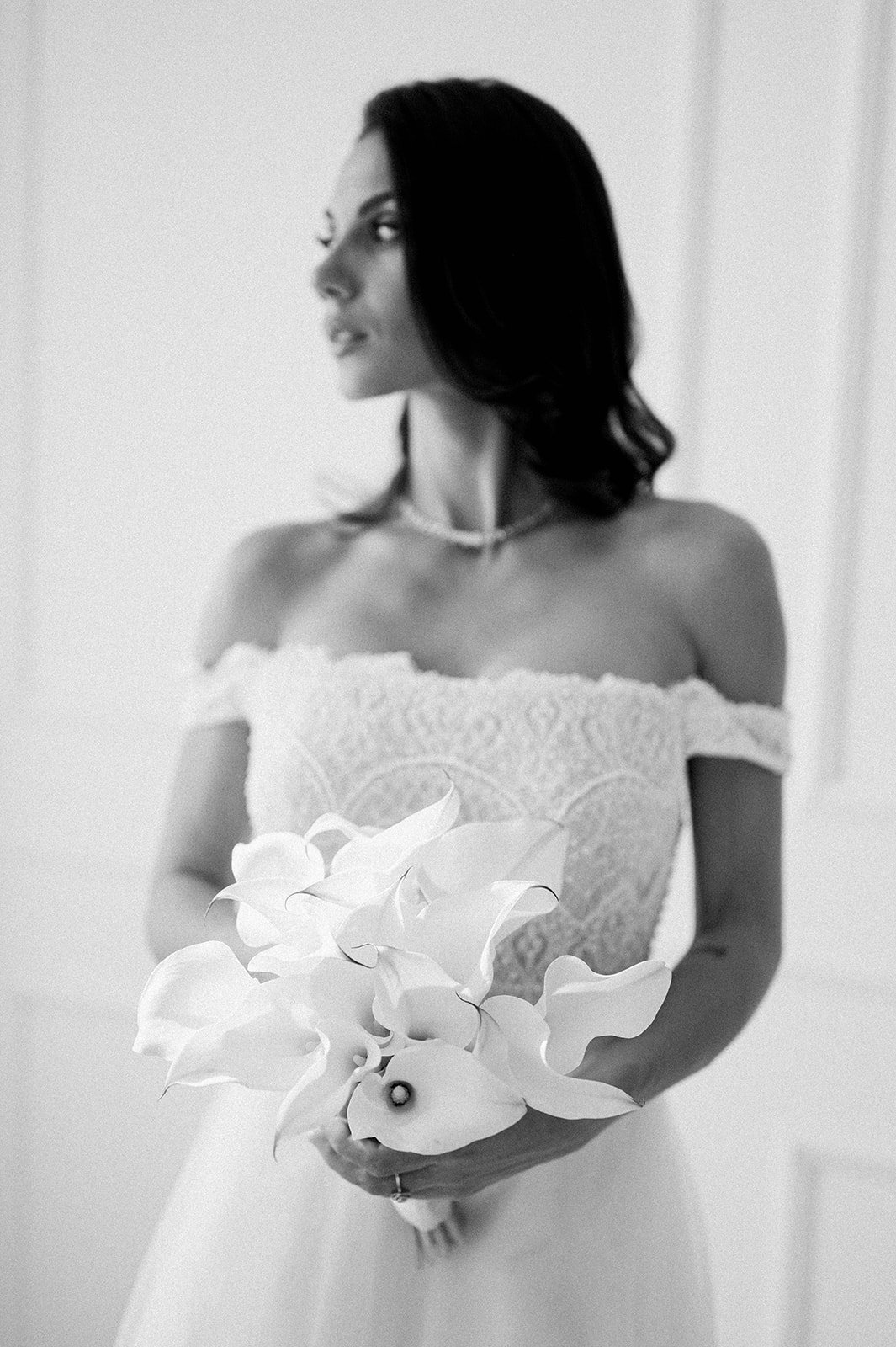 Portrait en noir et blanc d'une mariée tenant un bouquet d'arums blancs