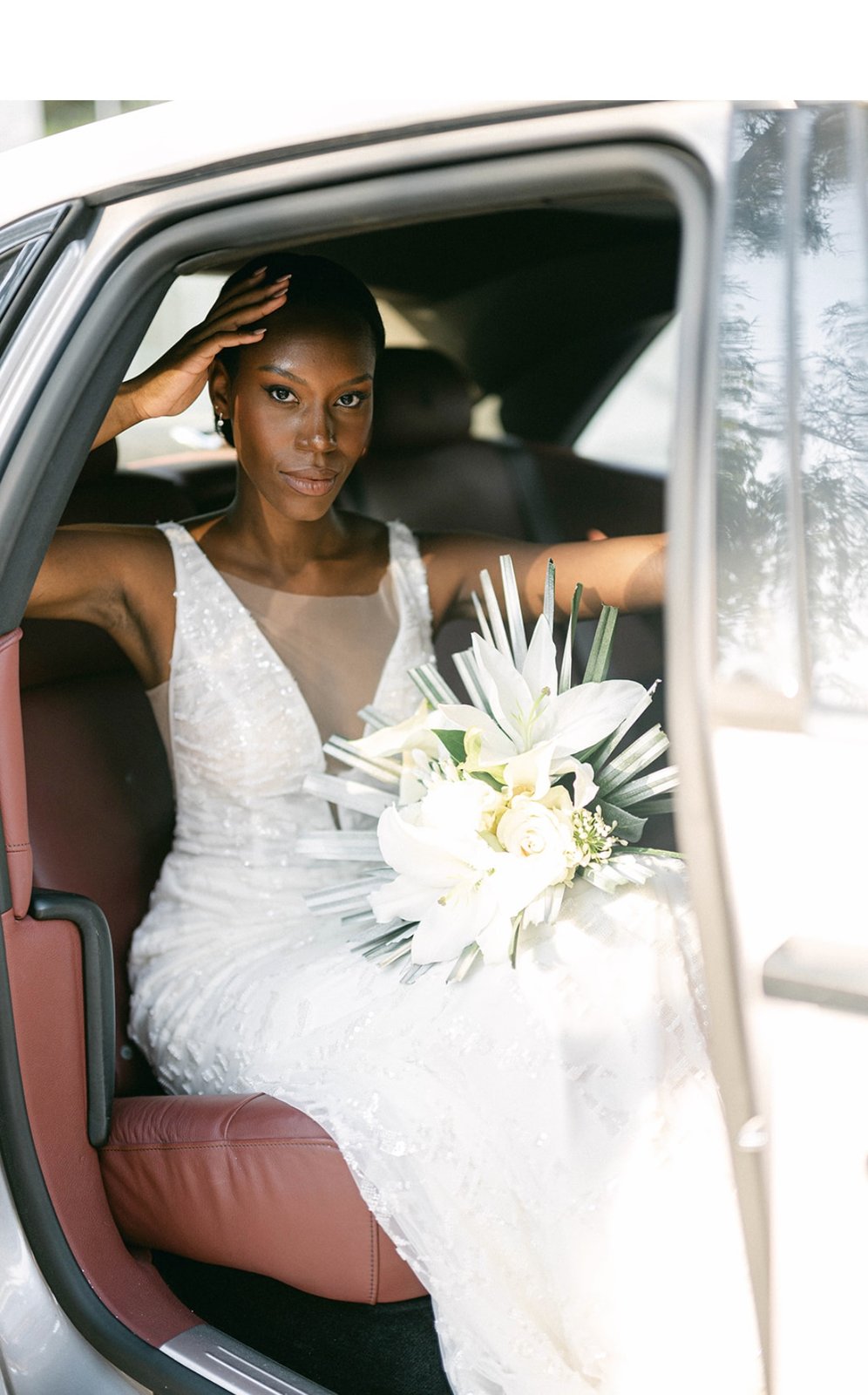 Mariée tenant un bouquet de lys blancs à l'arrière d'une voiture