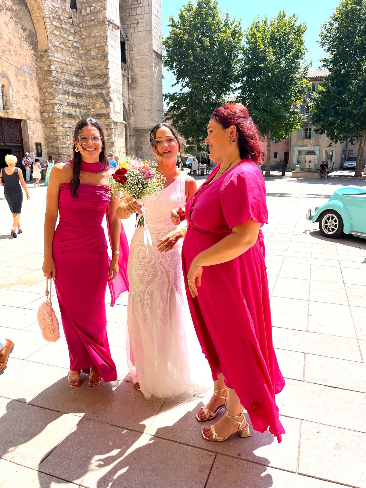Mariée et demoiselles d'honneur en robes fuchsia tenant un bouquet coloré sur une place
