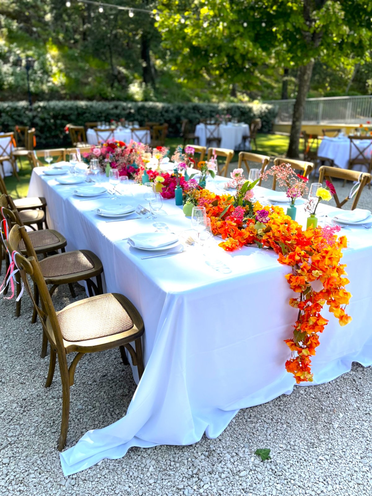 Table d'honneur décorée d'une cascade de fleurs orange et roses artificielles et fraîches
