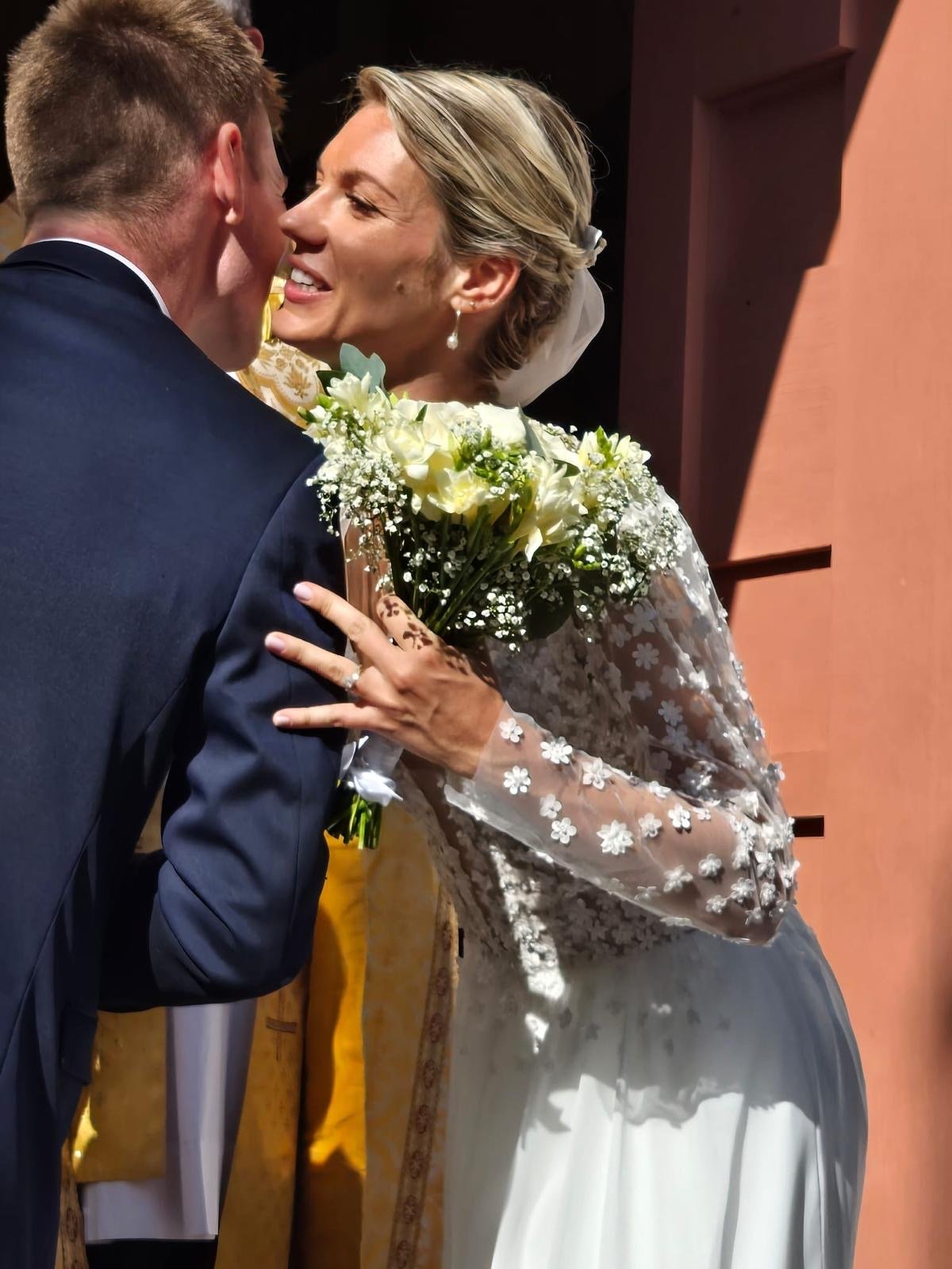 Mariés échangeant un moment complice devant l'église, bouquet de fleurs blanches