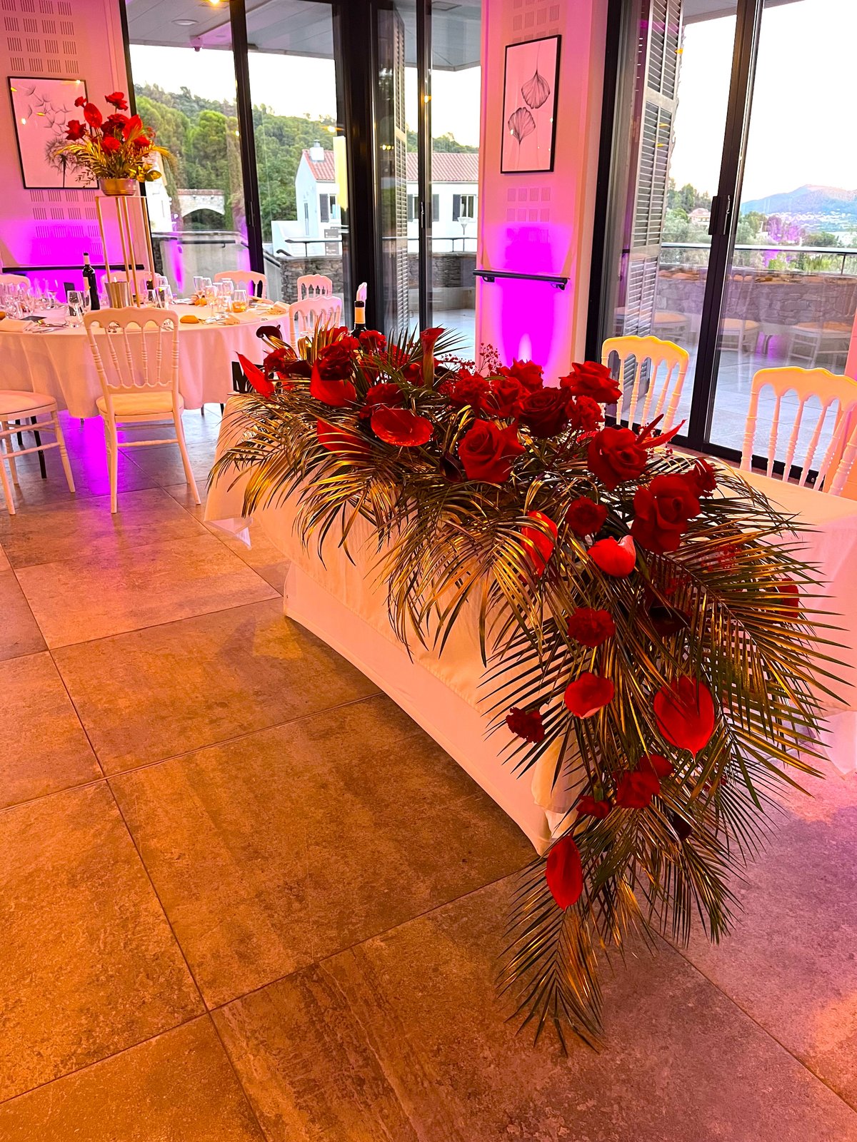 Table d'honneur en roses rouges et feuillage doré avec éclairage rose
