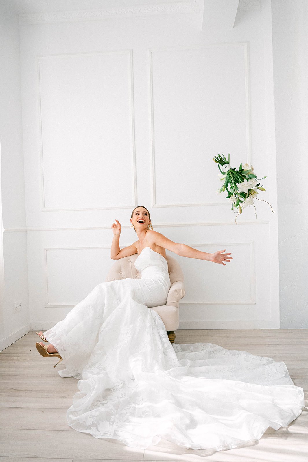 Mariée riant en lançant son bouquet de lys blancs
