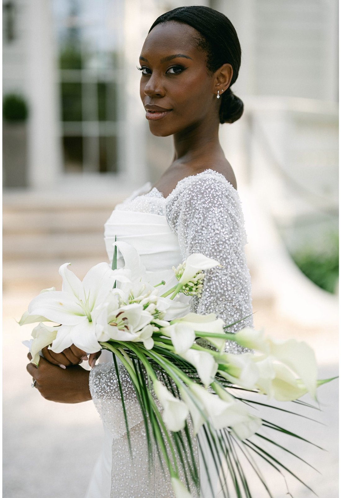 Portrait en noir et blanc de profil d'une mariée tenant un bouquet de lys