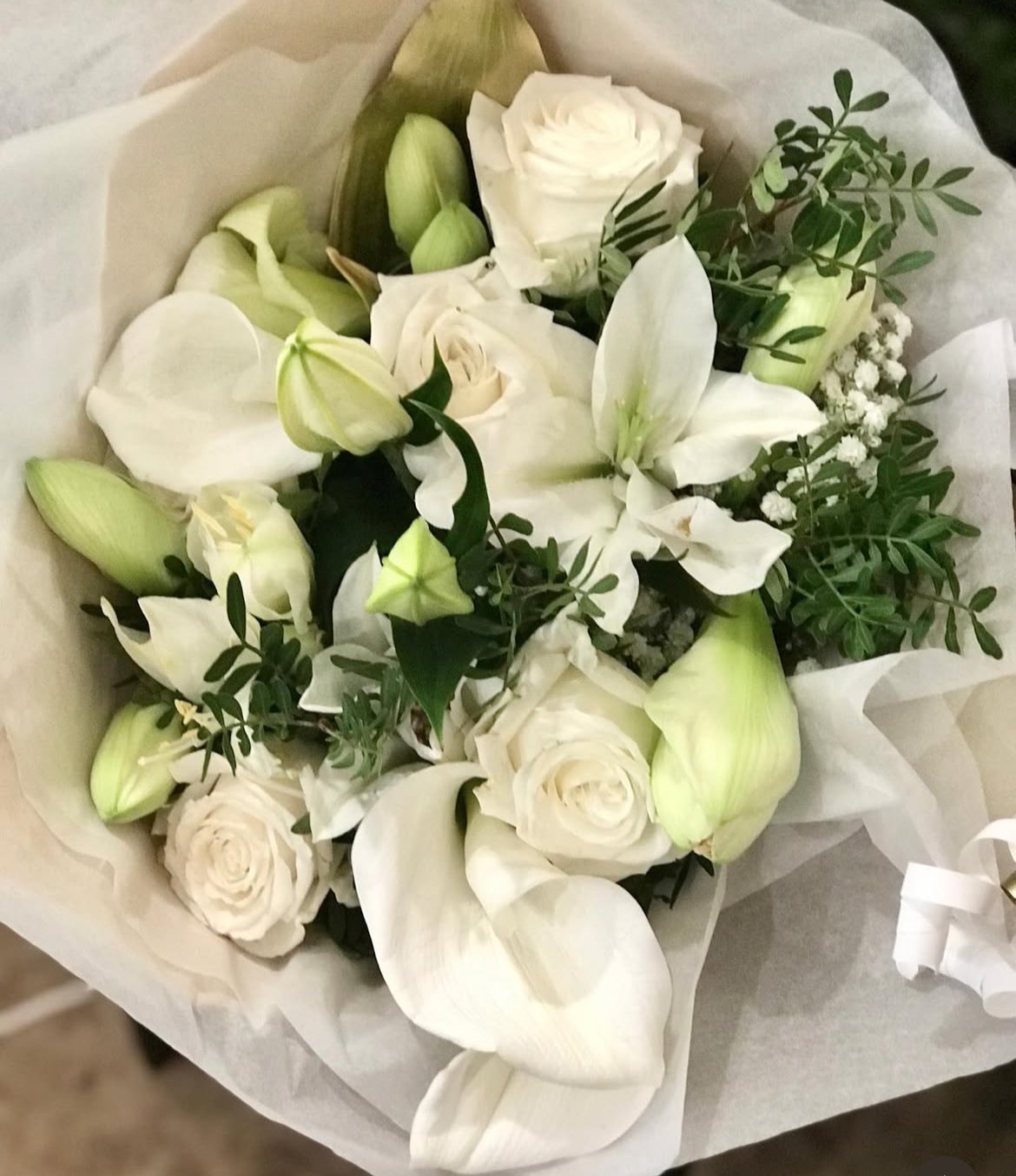 Bouquet de mariée rond en roses et lys blancs enveloppé de papier